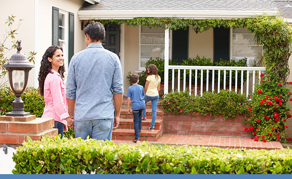 Family of parents and two kids in front of house